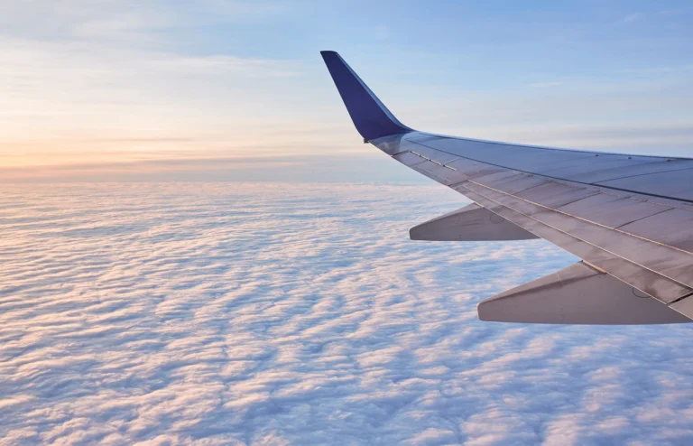An aircraft wing above clouds in warm evening light.