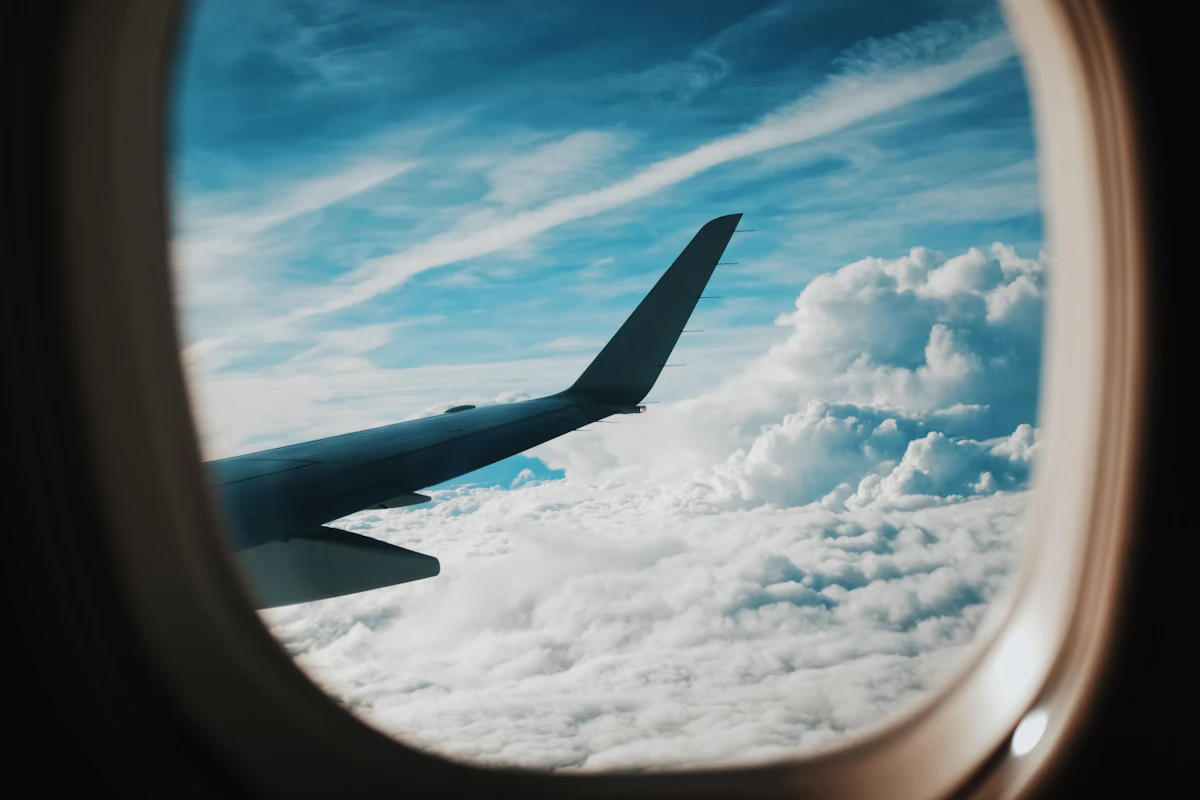 Aircraft wing and clouds seen through a cabin window.