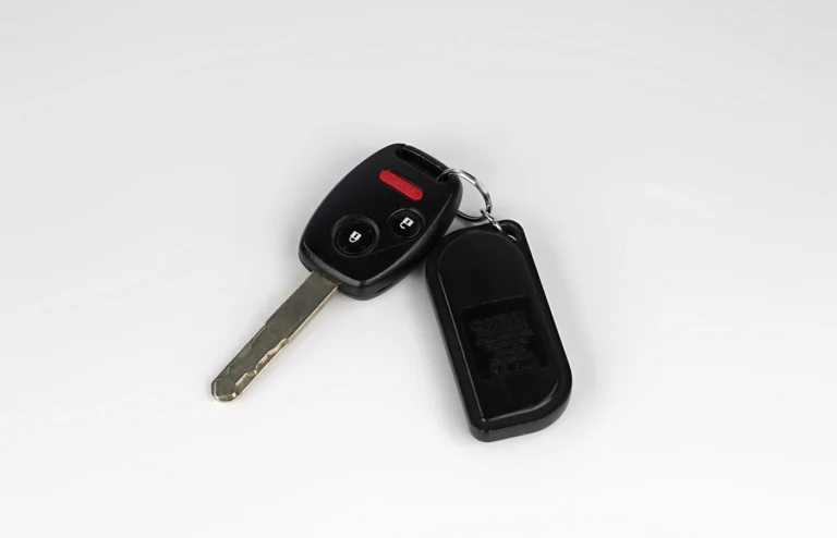 Car key and remote fob on a white surface.