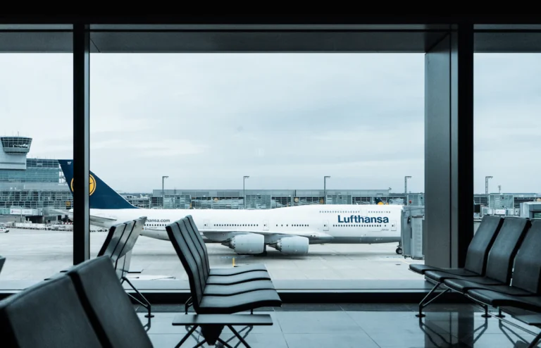 Empty airport seats beside windows overlooking an aircraft.