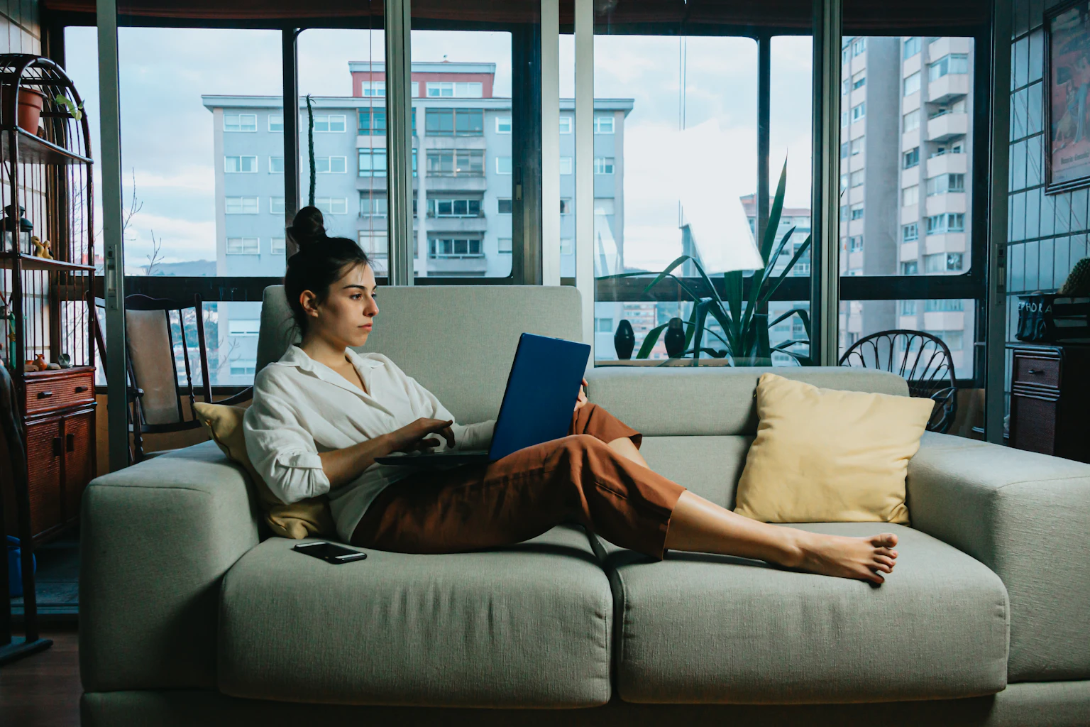 Woman using a laptop while sitting on a sofa at home