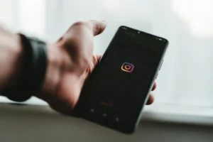 Hand holding a phone displaying the Instagram app