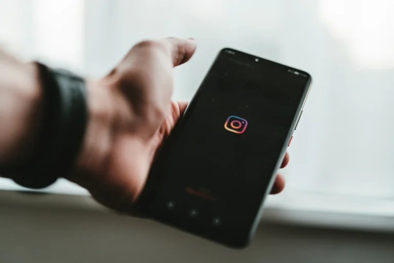 Hand holding a phone displaying the Instagram app