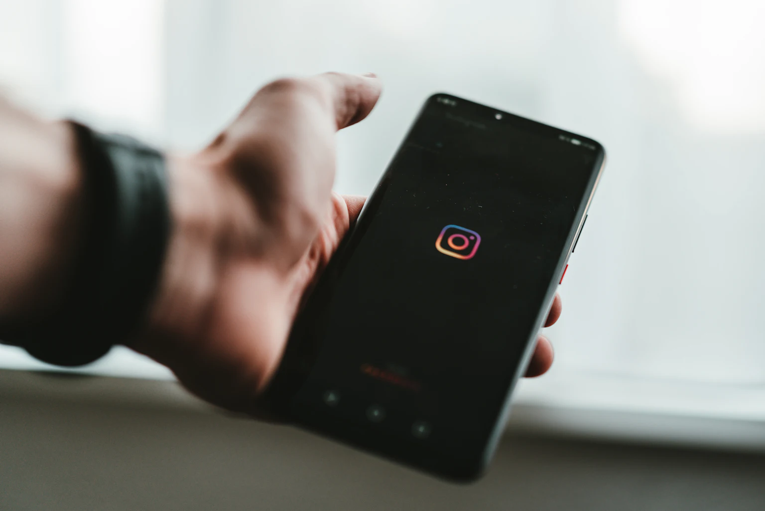 Hand holding a phone displaying the Instagram app