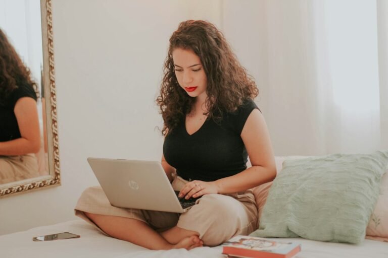Pregnant woman sitting on a sofa using a laptop