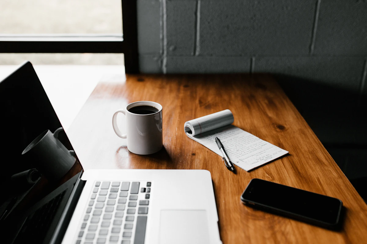 Laptop and notebook on a desk for preparing seasonal job applications