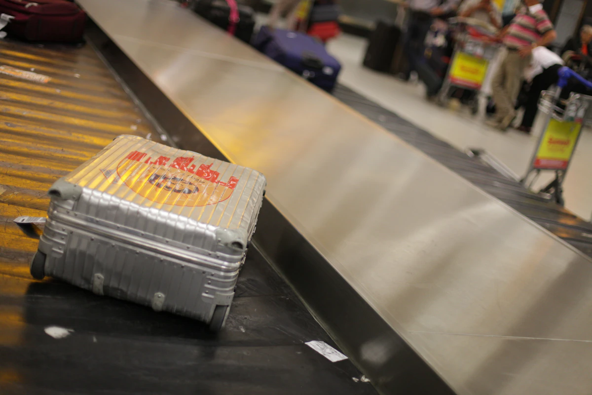 Cheap school holiday flights: suitcase on an airport baggage carousel, illustrating family luggage planning.