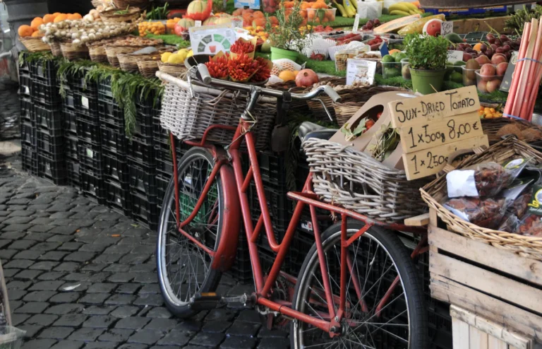 A bicycle beside a market stall displaying vegetables and packaged foods.