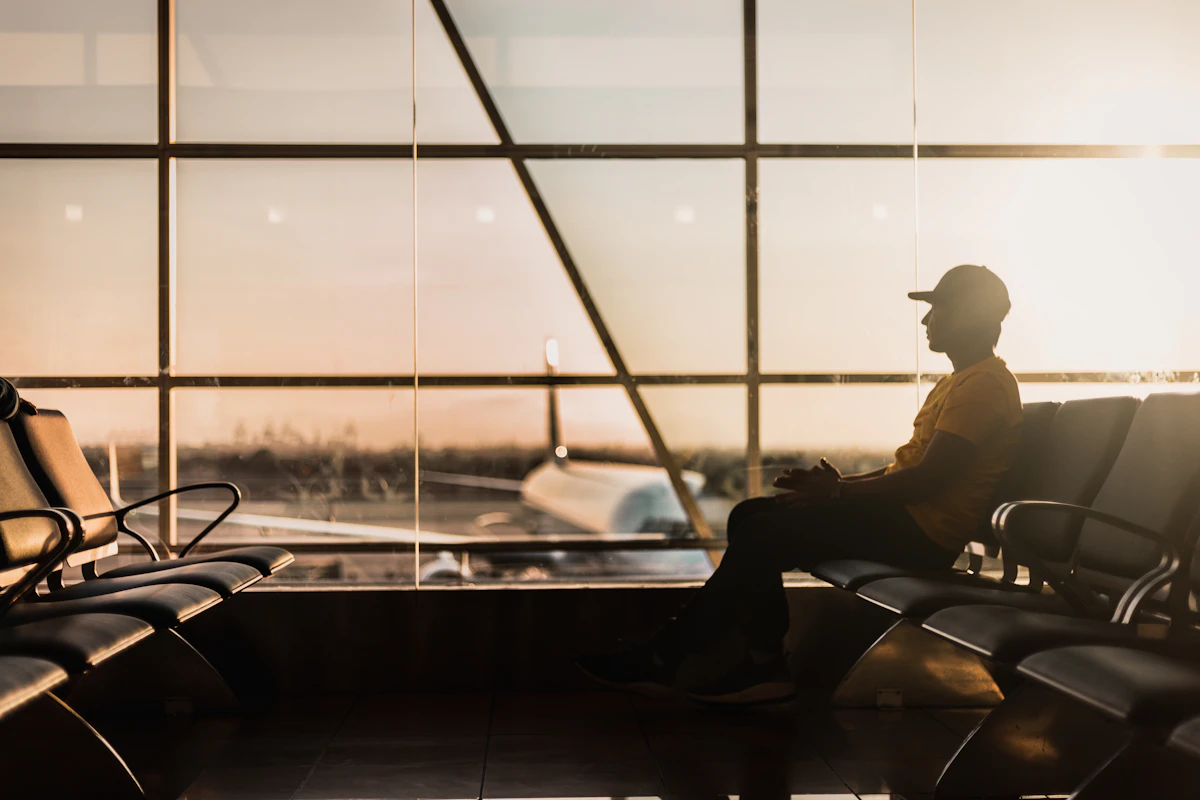 A traveller seated beside airport windows in warm evening light.